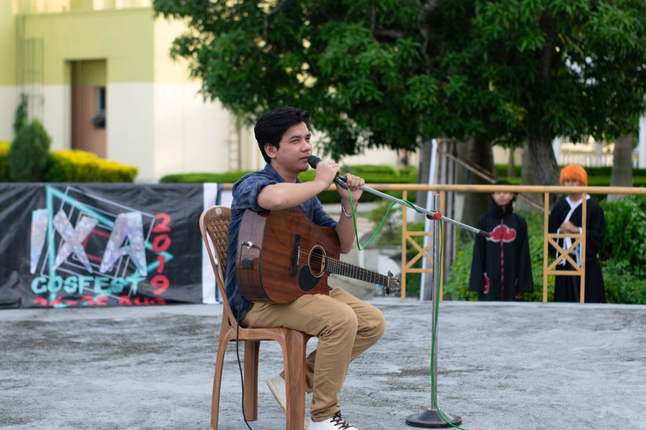 A performer playing acoustic guitar and singing at CosFest IXA 2019